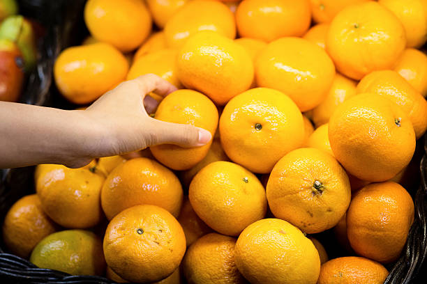 istock woman's hand choosing orange in supermarket 637311106
