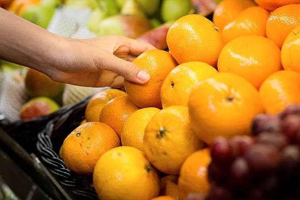 woman's hand choosing orange in supermarket