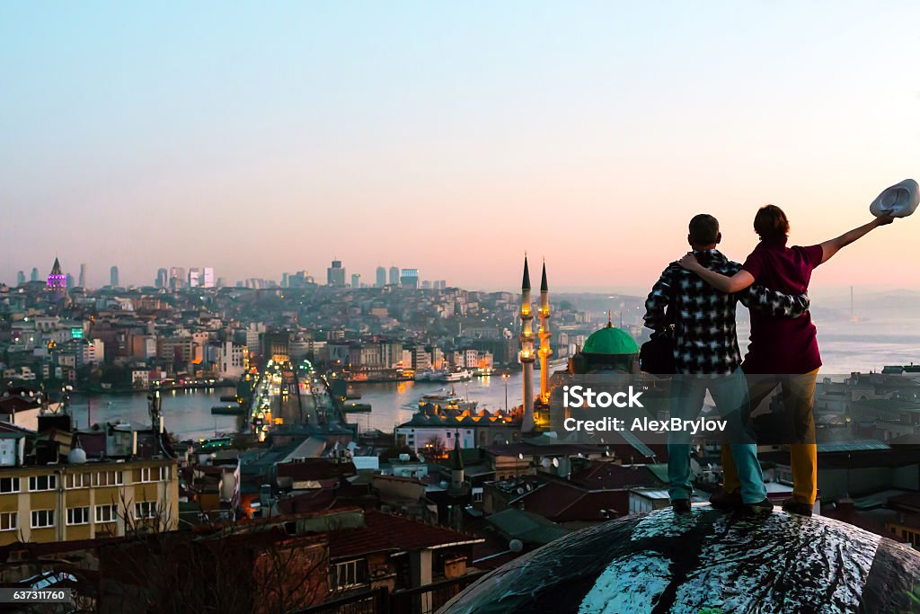 Homme et femme excités restant sur le toit surplombant la ville au lever du soleil - Photo de Istanbul libre de droits