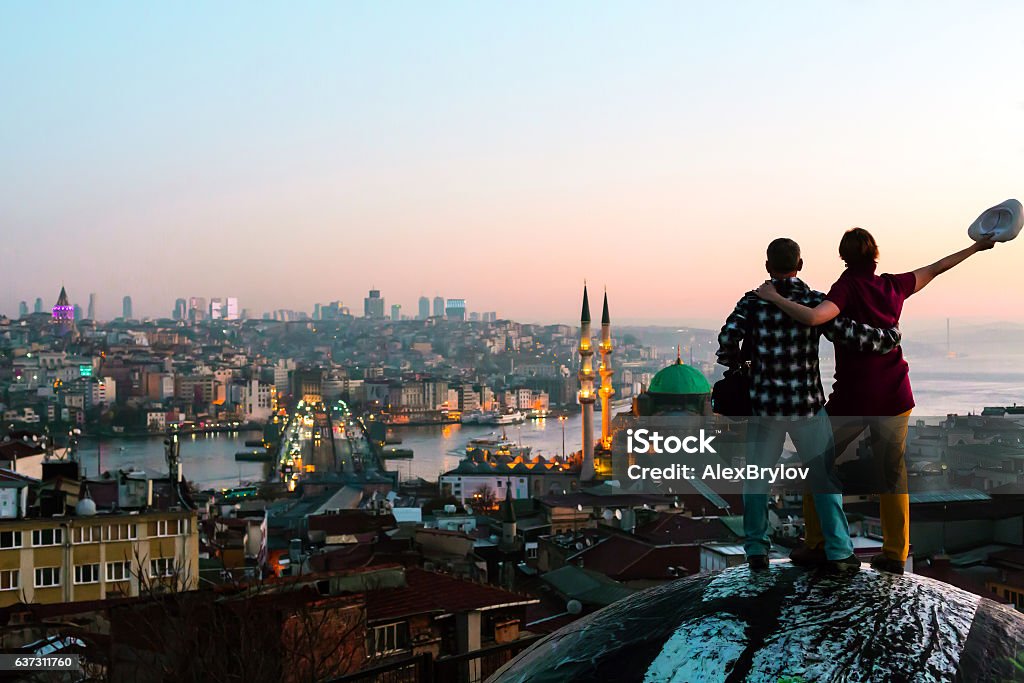 Uomo e donna eccitati che soggiornano sul tetto con vista sulla città all'alba - Foto stock royalty-free di Istanbul