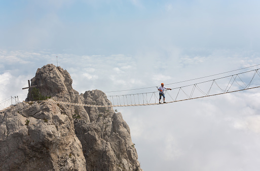 Man crossing the chasm on the hanging bridge (focus on the man)