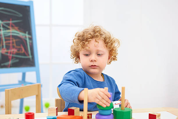 Little boy playing with wooden pyramid at table