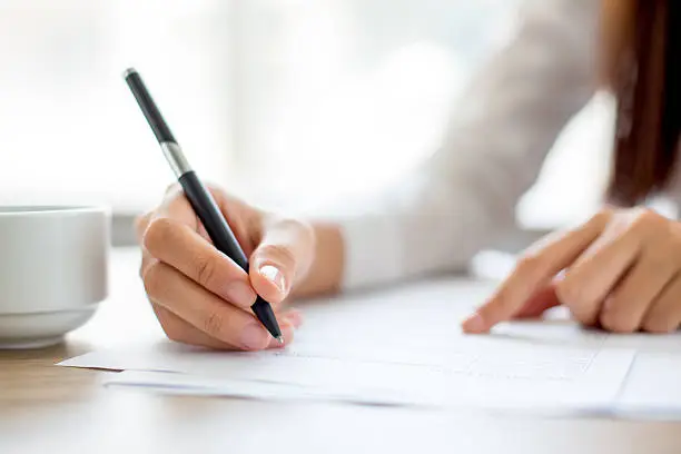 Photo of Hand of businesswoman writing on paper in office