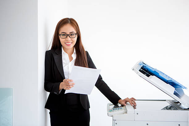 istock Positive young businesswoman standing at printer 637317156