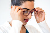 Serious young businesswoman putting on eyeglasses