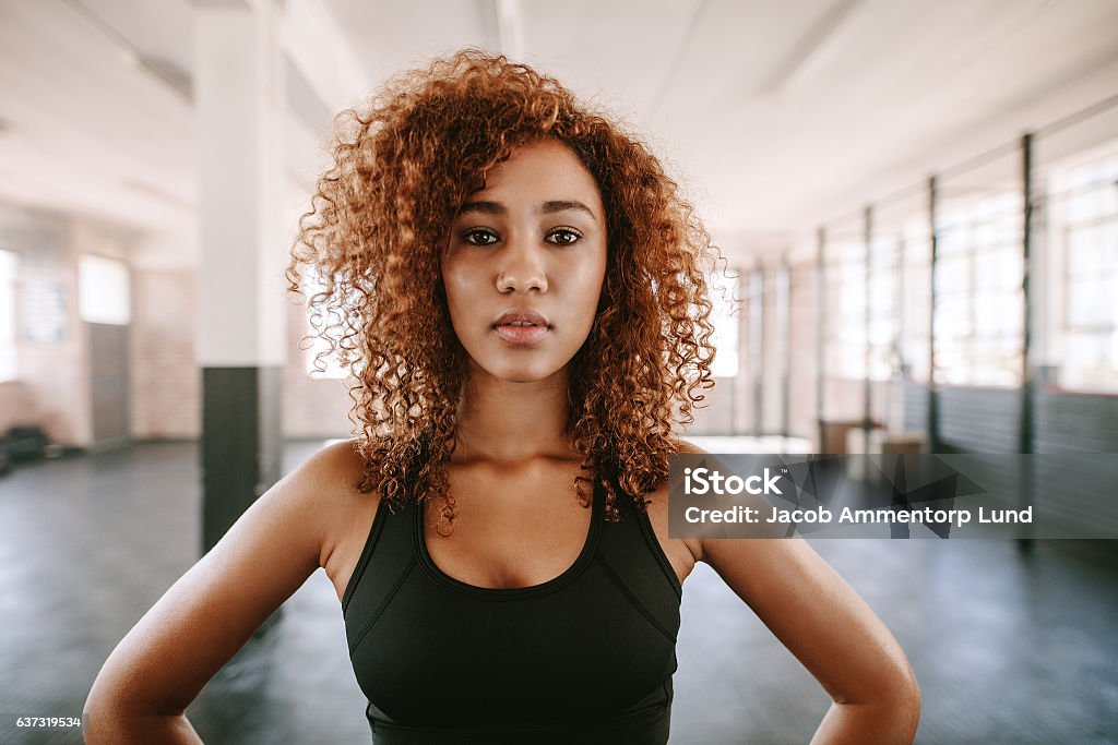 Beautiful afro american female with curly hair in gym Portrait of beautiful afro american female with curly hair in gym. African fitness woman at healthclub. Women Stock Photo