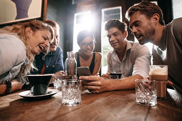 istock Friends looking at mobile phone while sitting in cafe 637321720