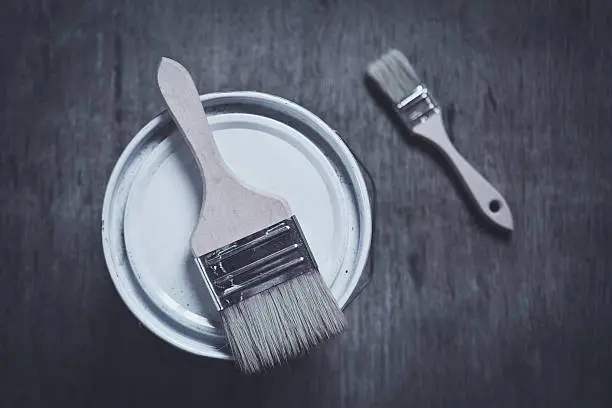 two paint brushes on cans and wooden board