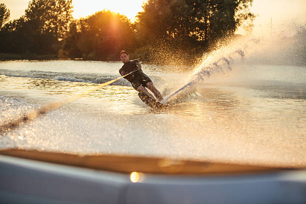 uomo wakeboard sul lago dietro barca - wakeboarding foto e immagini stock
