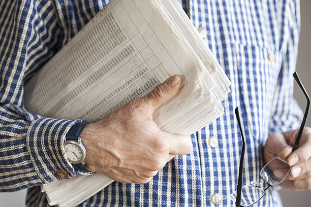 istock Man holding newspaper and eyeglasses 637325128