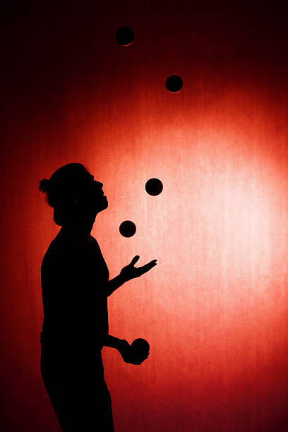 silhouette d’un jongleur avec des boules sur fond rouge - back lite photos et images de collection