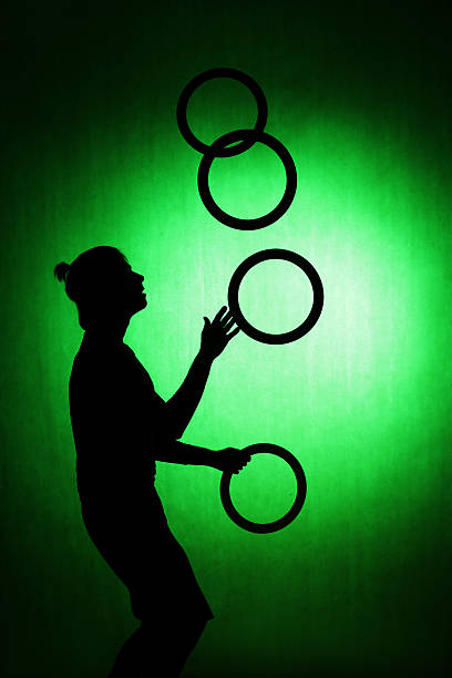 silhouette d’un jongleur avec des anneaux sur fond vert - back lite photos et images de collection