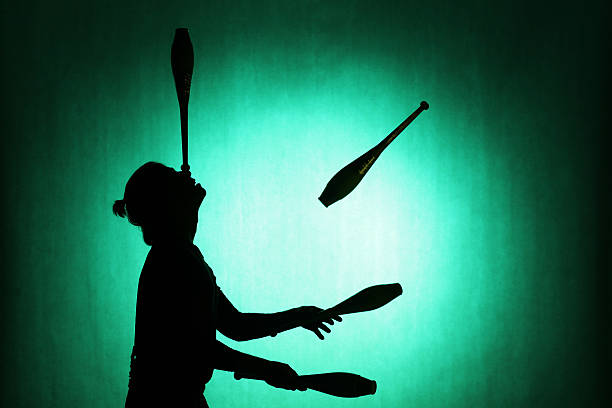 silhouette of a juggler with sticks on a blue background - jongleren stockfoto's en -beelden