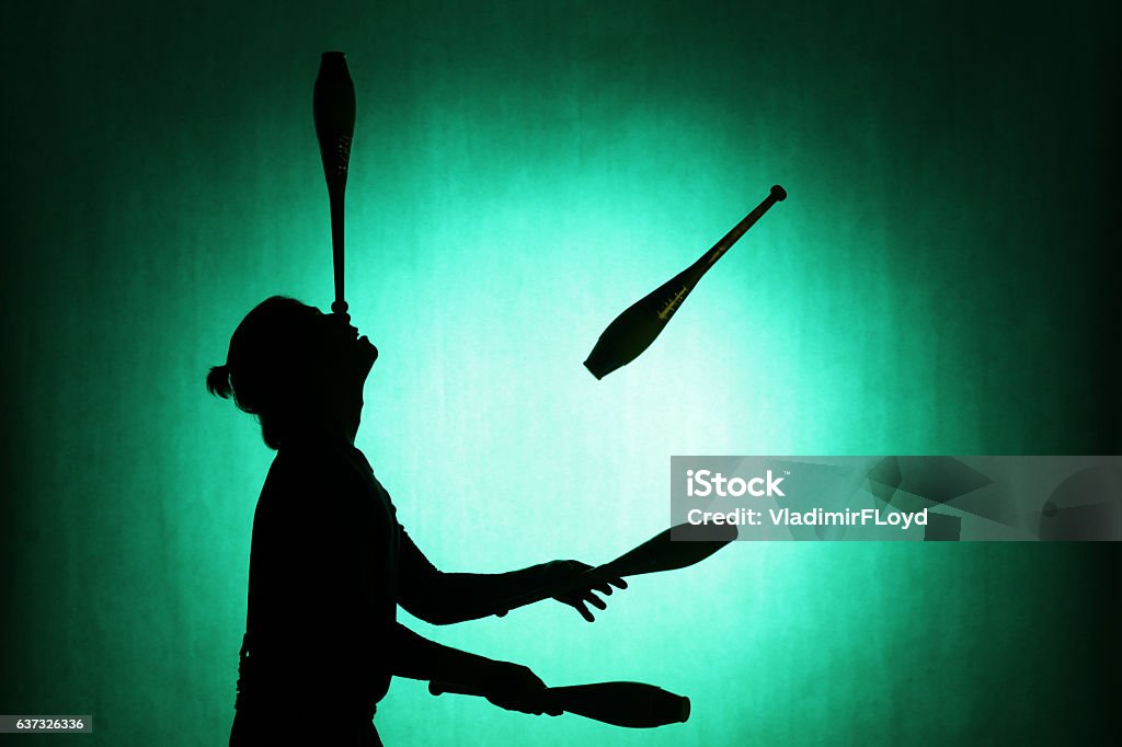silhouette of a juggler with sticks on a blue background Juggling Stock Photo