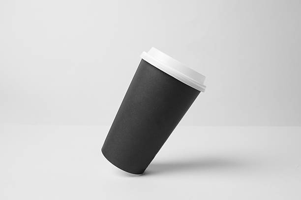 Blank black paper cup with white cap in the air
