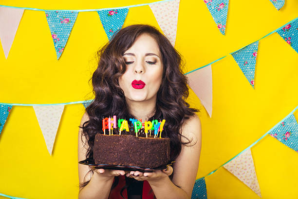 Beautiful caucasian girl blowing candles on her cake.Celebration and party Beautiful caucasian girl blowing candles on her cake. Celebration and party. Having fun. Young pretty woman in red dress  is laughing. woman birthday cake stock pictures, royalty-free photos & images