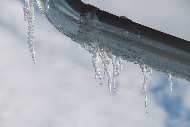 istock Snowy ice Icicles hanging on a roof house 637328904
