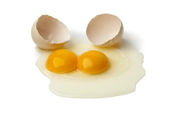 Broken raw double yolk egg on white background