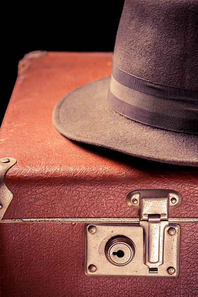 istock Vintage brown suitcase with vintage hat on black background 637331978