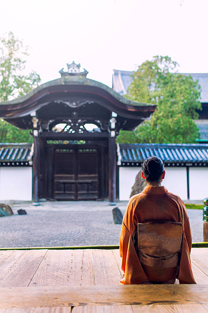 Woman in kimono kneeling at temple in early morning stock photo