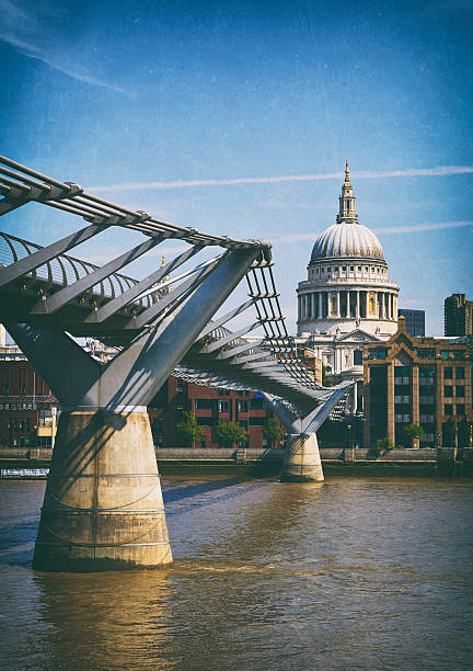 The Millennium Bridge stretches across the Thames towards the iconic shape of St Paul's Cathedral. Processed to resemble a vintage photo.