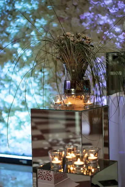 Photo of floral arrangement in a glass vase and candles