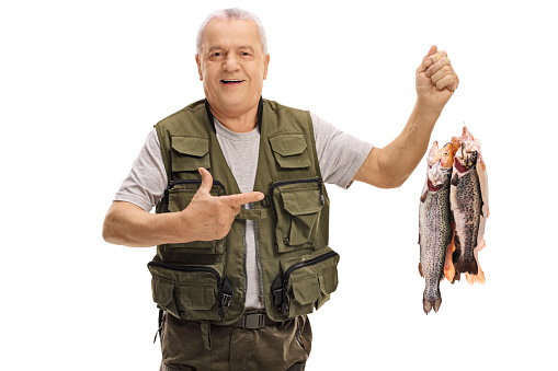 Joyful mature fisherman holding freshly caught fish and pointing isolated on white background