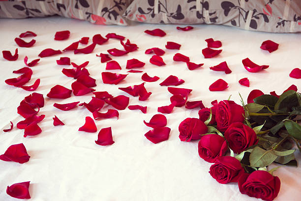 istock bouquet red roses and his scattered petals on a bed 637337030