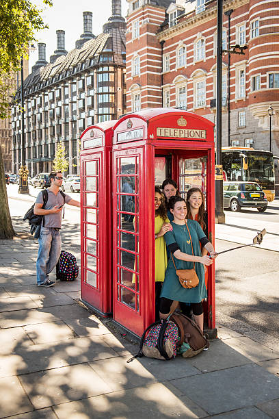 Young girls in a phone box, London London, United Kingdom - September 11, 2016: A group of young girls take pictures of themselves with a mobilephone in a phone box. london girl stock pictures, royalty-free photos & images