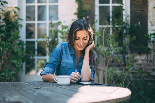 Woman drinking tea and reading a book in the garden