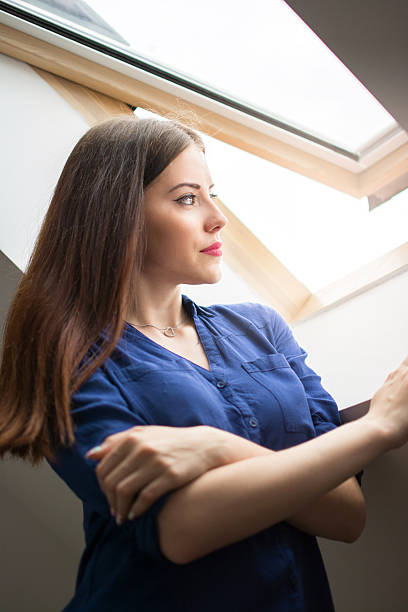 istock Young woman looking through attic window. 637343320