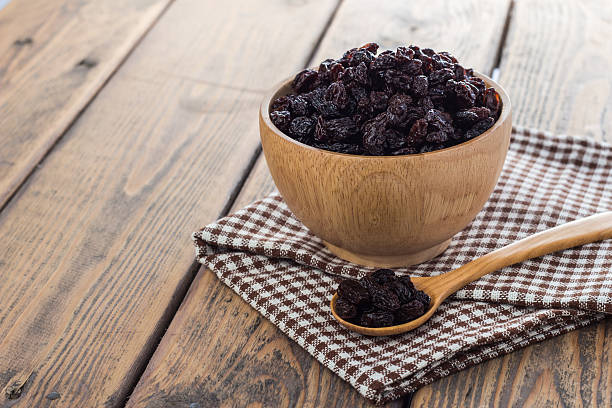 Dried raisins. Dried raisins in wooden cup and spoon on wooden table. raisin stock pictures, royalty-free photos & images