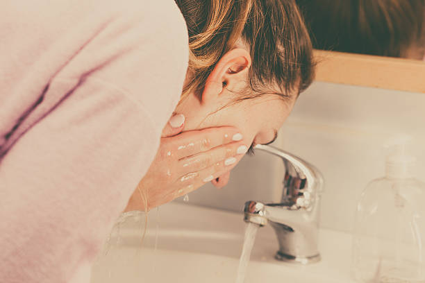 woman washing face in bathroom. hygiene. - gezicht wassen stockfoto's en -beelden