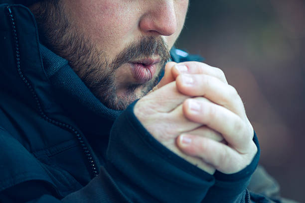 homme soufflant dans ses mains - grelotter photos et images de collection