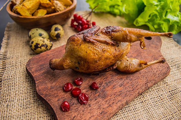 Roasted quail with greens on a wooden Boards. Top view