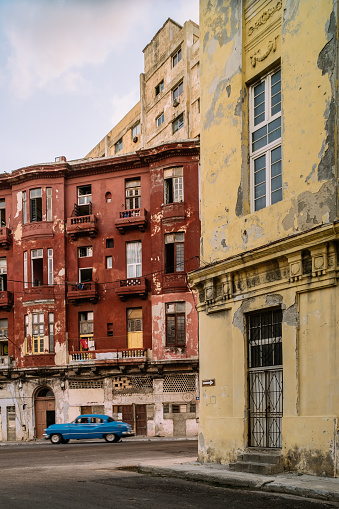 Havana, Cuba - October 10, 2016: Old Havana quarter street intersection in the evening. Rough facades of old colonial apartment buildings.  Local traffic passing by. Typical scene all around old Havana, where ever you see old buildings with people still living inside. Variety of colours and styles. Beauty of old architecture neglected over many years with out upkeep. Evening in Havana.