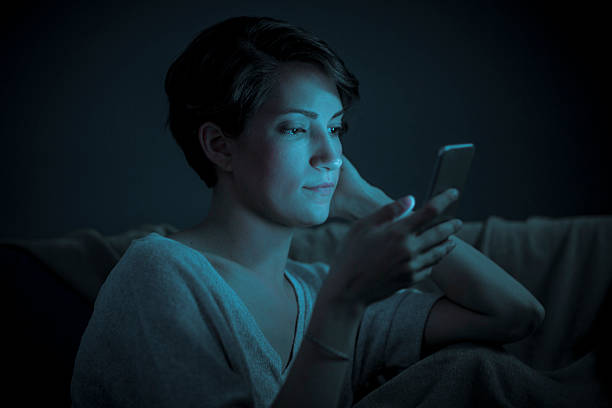 Close Up of a Woman on Her Smart Phone A close up of a woman illuminated by the glow of her smart phone at night (stock image). mobile phone lights up stock pictures, royalty-free photos & images