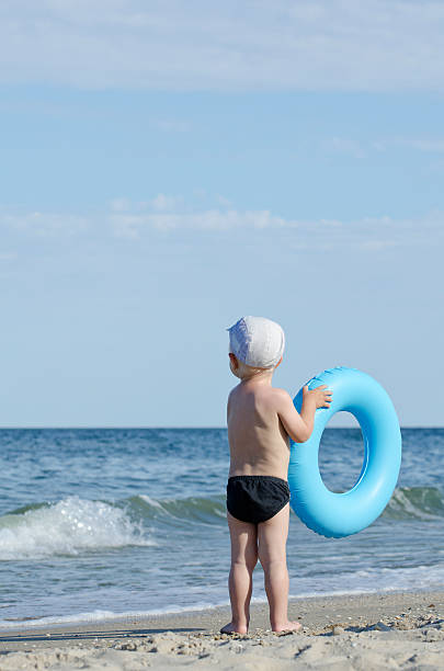 istock Kid in swimming trunks and cap with a swimming circle 637360482