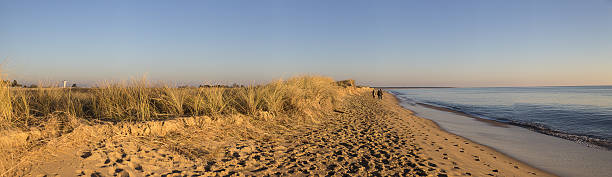 istock panoramic view with people walking on the beach at sunset 637361260