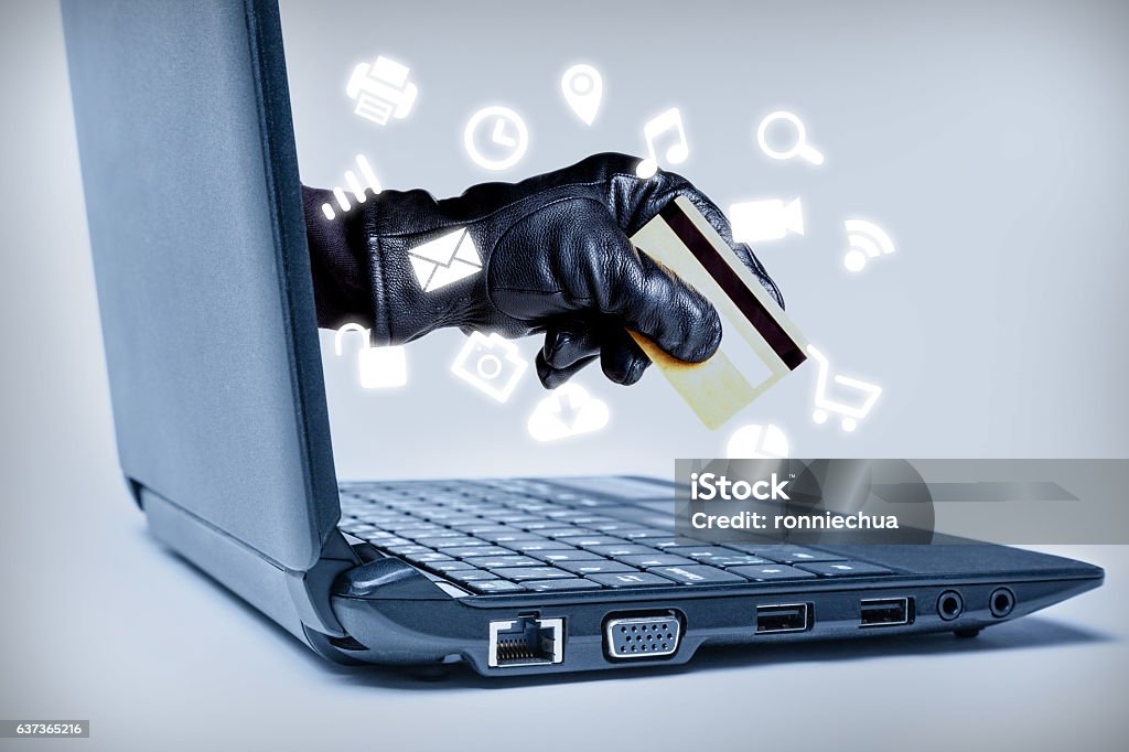 Cyber Crime Concept A gloved hand reaching out through a laptop holding debit or credit card with common media icons flowing, signifying a cybercrime or Internet theft while using various Internet media. Phishing Stock Photo