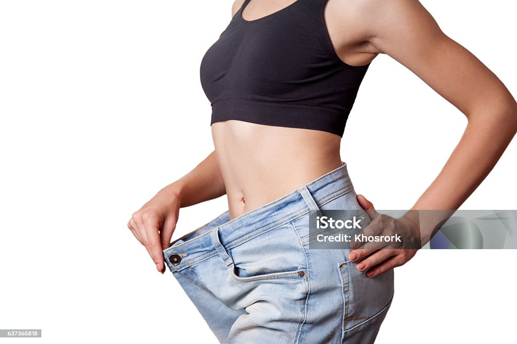 diet concept and hanppy woman Close-up of slim waist of young woman in big jeans showing successful weight loss, isolated on white background, diet concept. Loss Stock Photo