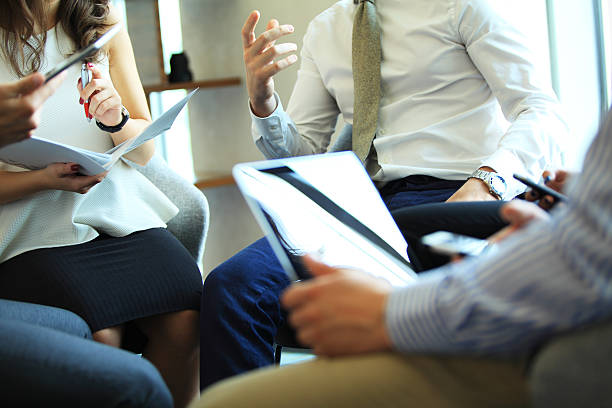 Close-up of people sitting on conference together and making notes.