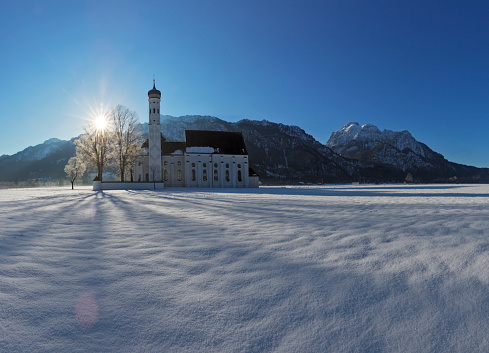 Panorama landscape in Bavaria at winter with landmark church St. Coloman and alps mountains near by city Fuesen