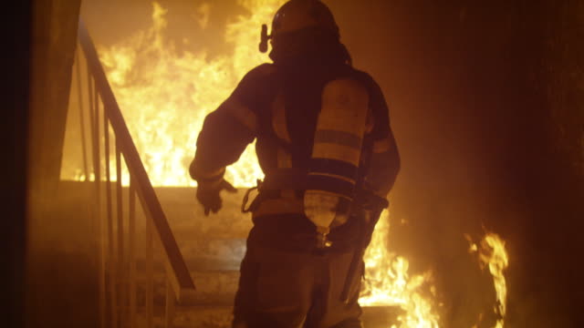 Brave Firefighter Runs Up The Stairs. In Slow Motion. Raging Fire is Seen Everywhere.