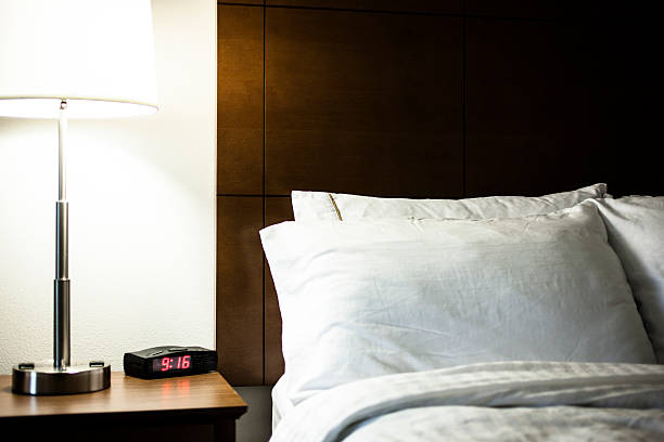 istock Hotel room bed with pillows, end table, lamp, and duvet. 637371366