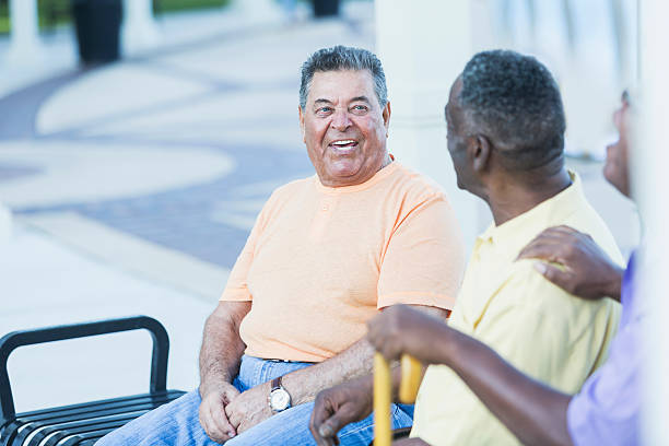 istock Elderly man hanging out with friends on park bench 637371378