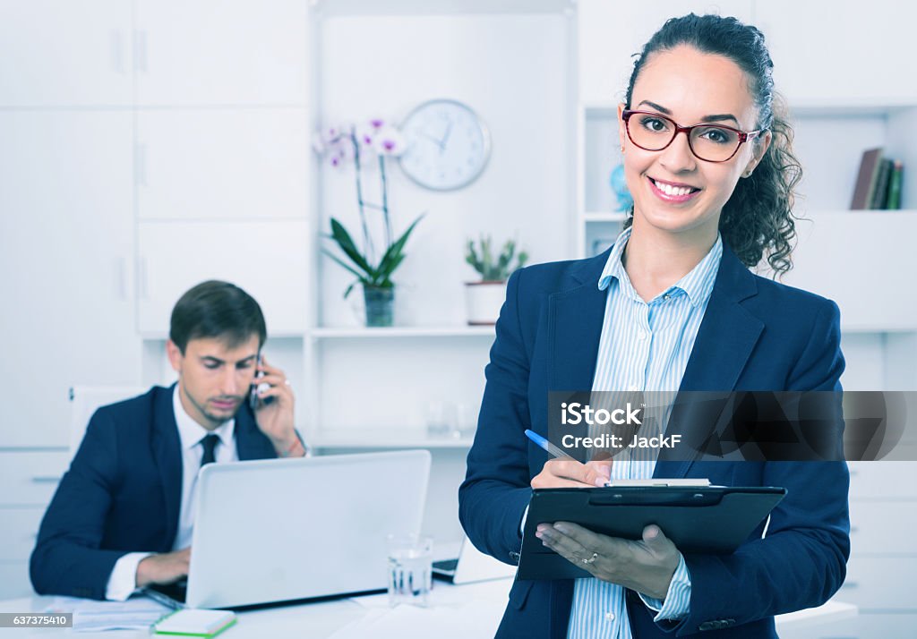 Glad business female secretary having cardboard in hands Glad positive efficient business female secretary having cardboard in hands and working in office Secretary Stock Photo