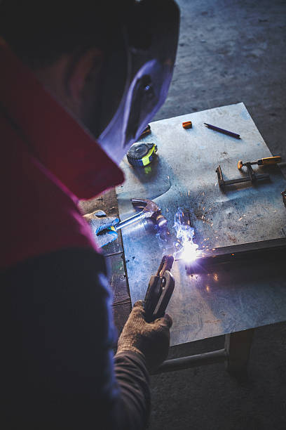 istock Young man welding metal overhead shot 637379352