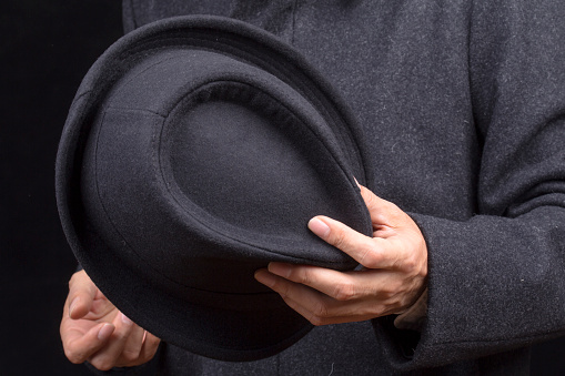 hand holding a black fedora hat