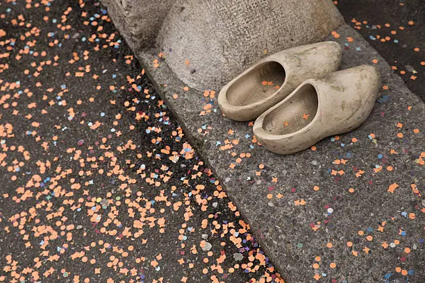 A pair of typical wooden shoes from a Waggis in front of the entrance of a house surrounded by orange confetti.
